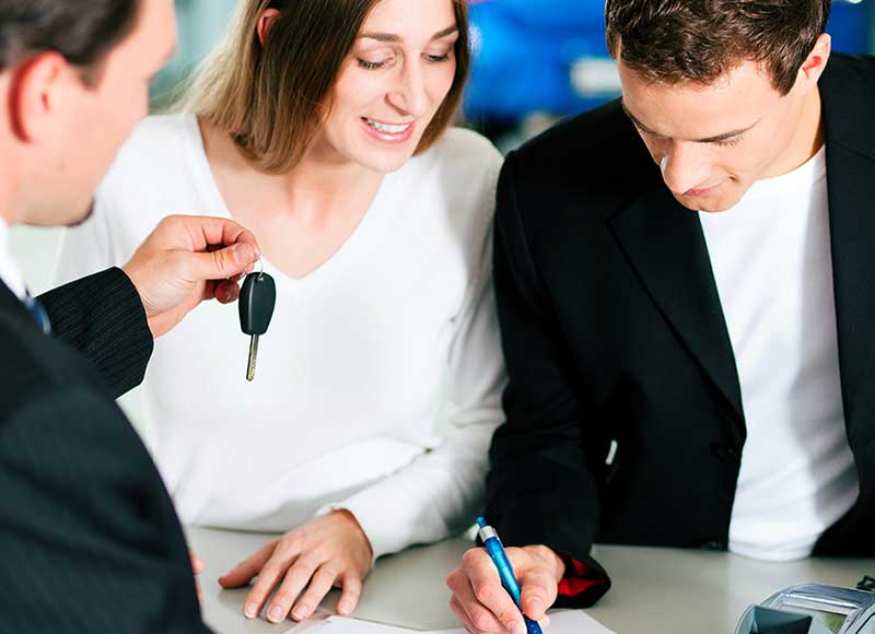 A person wearing a business suit hands over a car key